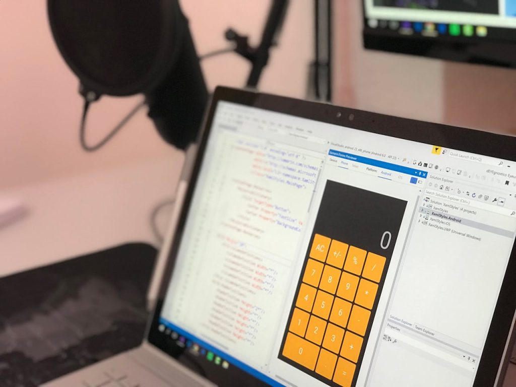 gray-laptop-computer-showing-calculator-application-with-codes-907487 Close-up of a laptop displaying code and a calculator app in a modern workspace.